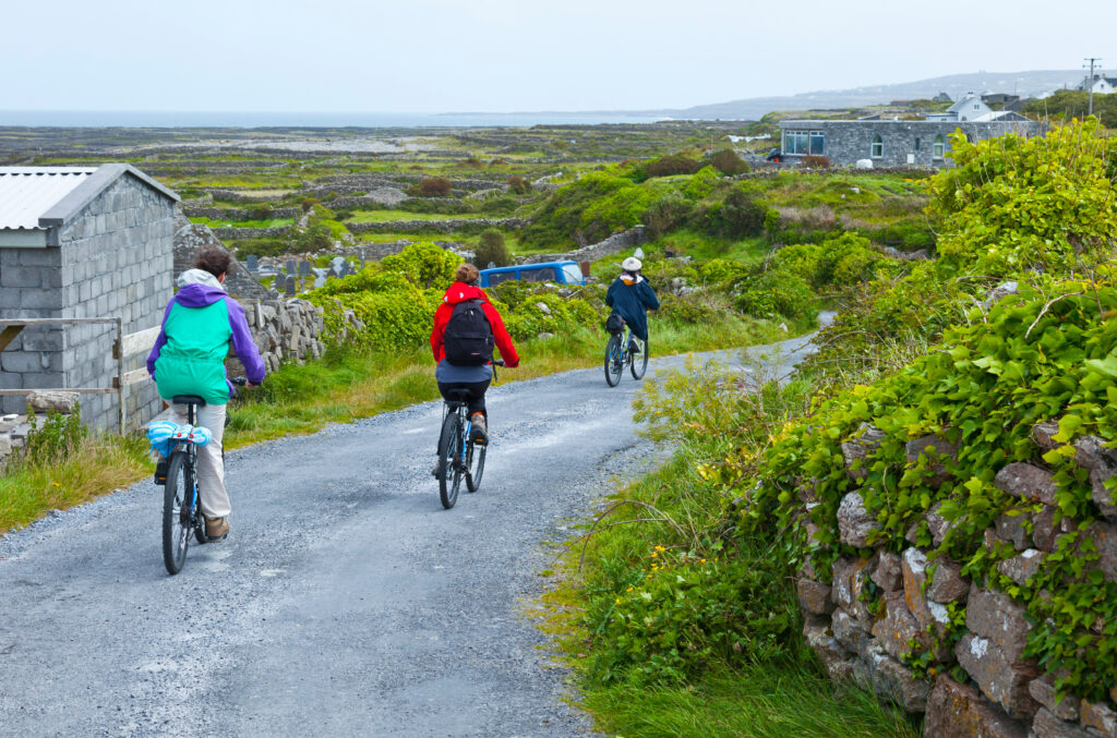 Students cycling a stone-walled country lane on Inis Mór in the Aran Islands, Ireland